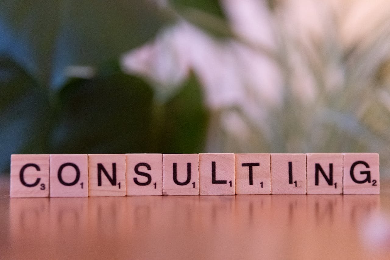 Wooden letter tiles spelling Consulting with a blurred background. Ideal for business concepts.